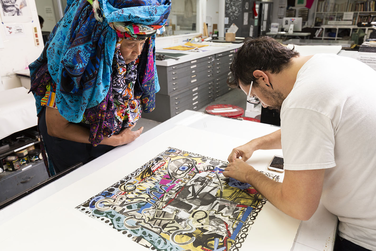 Close-up photo of Chakaia Booker and Justin Sanz working on a print in a print shop.