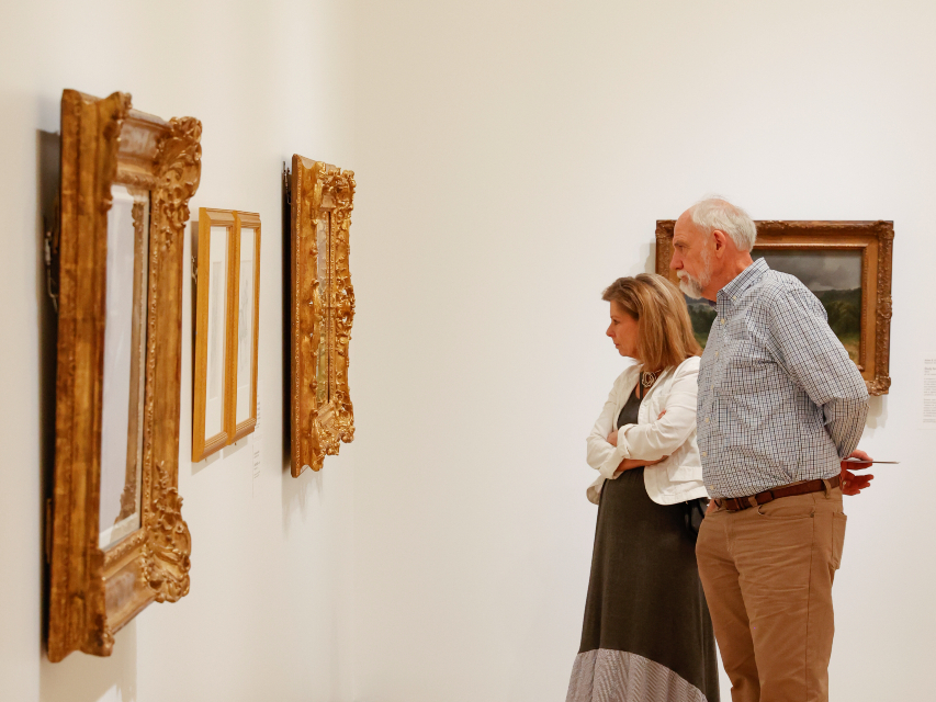 Photo of a man and woman looking at artwork hanging in an art gallery.