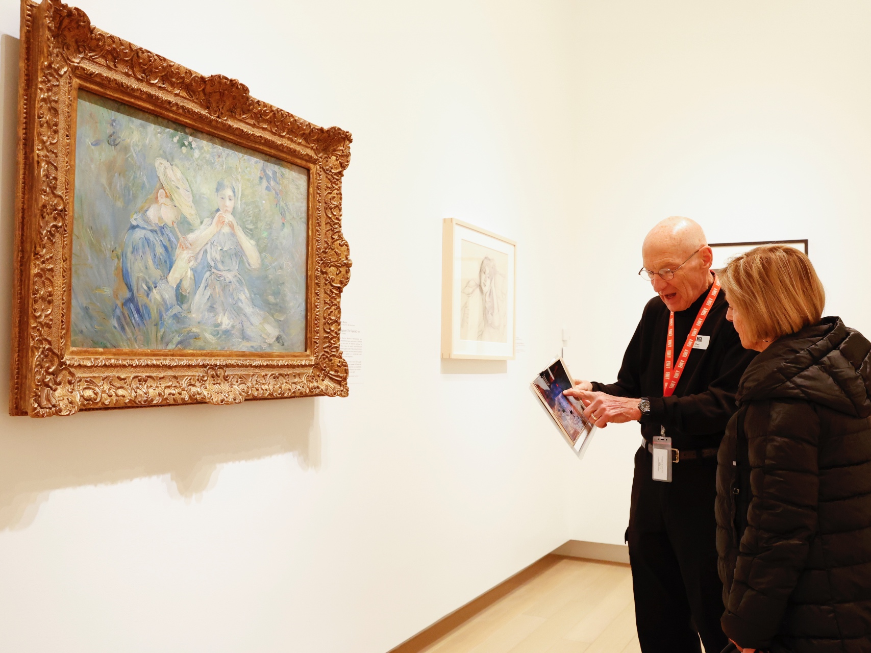 Photo of an AMFA docent speaking to a woman in front of a painting in an art gallery.