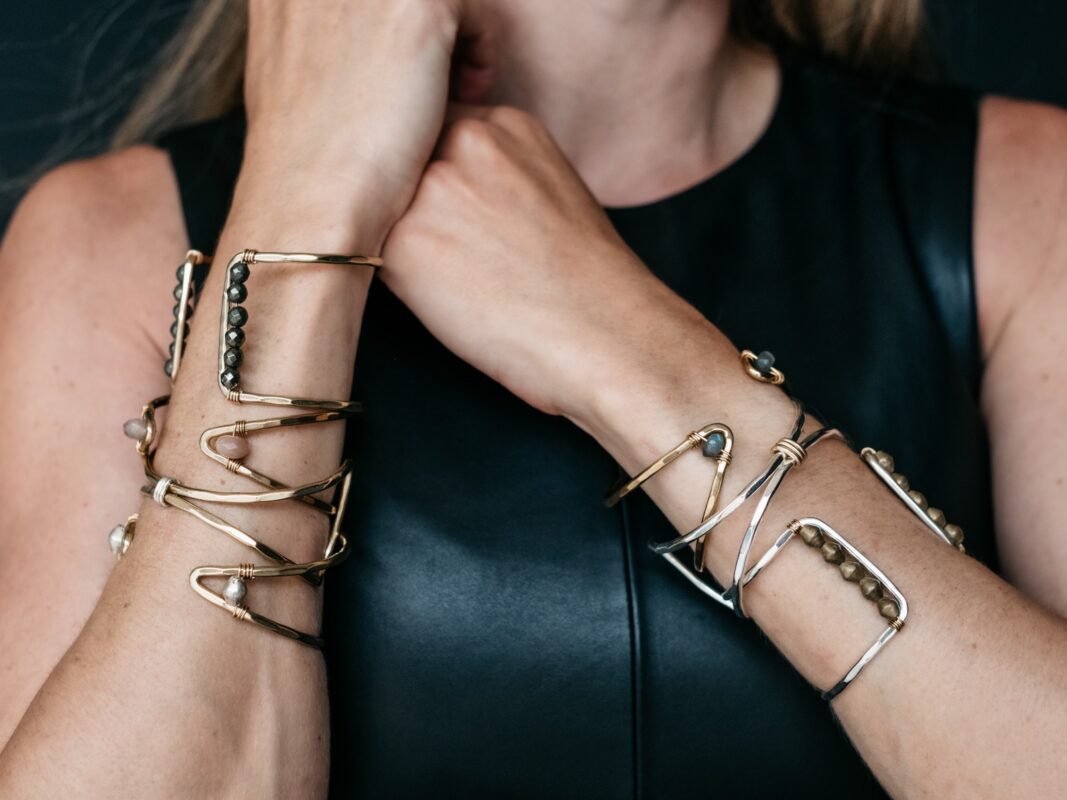 Close-up photo of metal bracelets on a woman's arms.