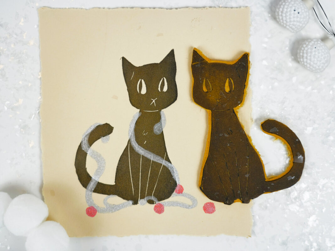 Photo of a card stamped with an image of a brown cat wrapped in silver garland.