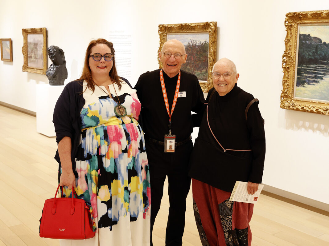 Photo of an AMFA docent posing with two guests in an art gallery.
