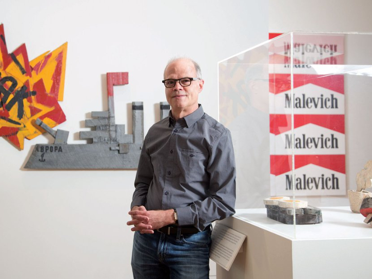 Photo of Neil K. Rector in an art gallery standing next to work of pop art.