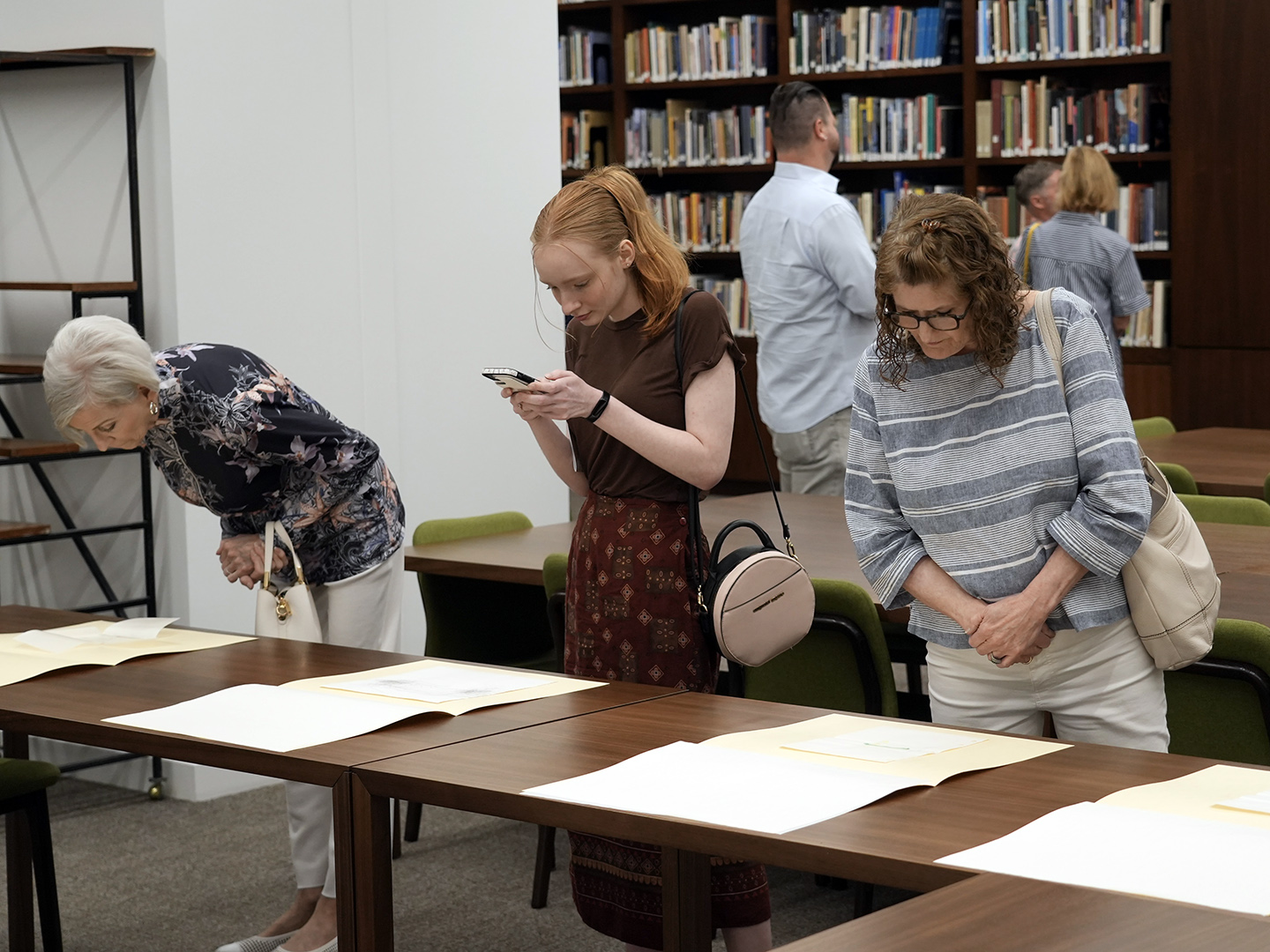 Photo of three women looking at drawings on a table.
