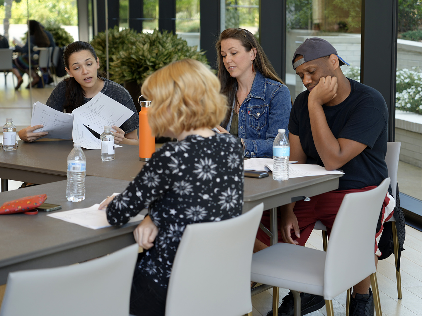 Photo of people gathered around a table reading scripts.