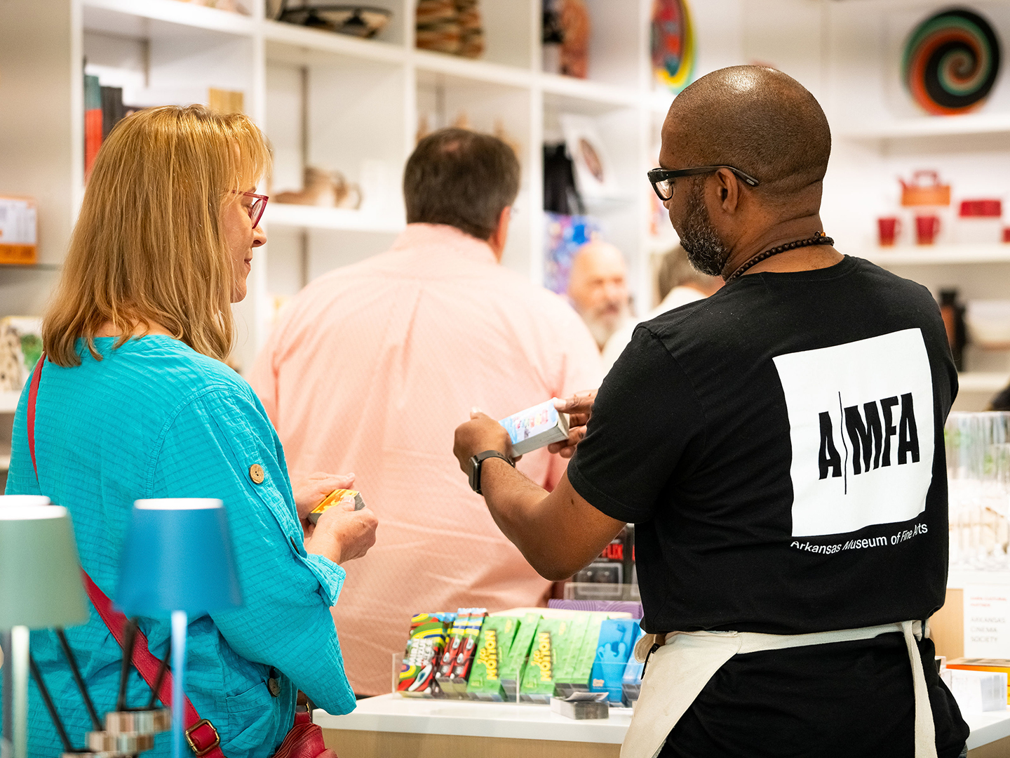 Photo of a store clerk showing a product to a woman in the AMFA Museum Store.