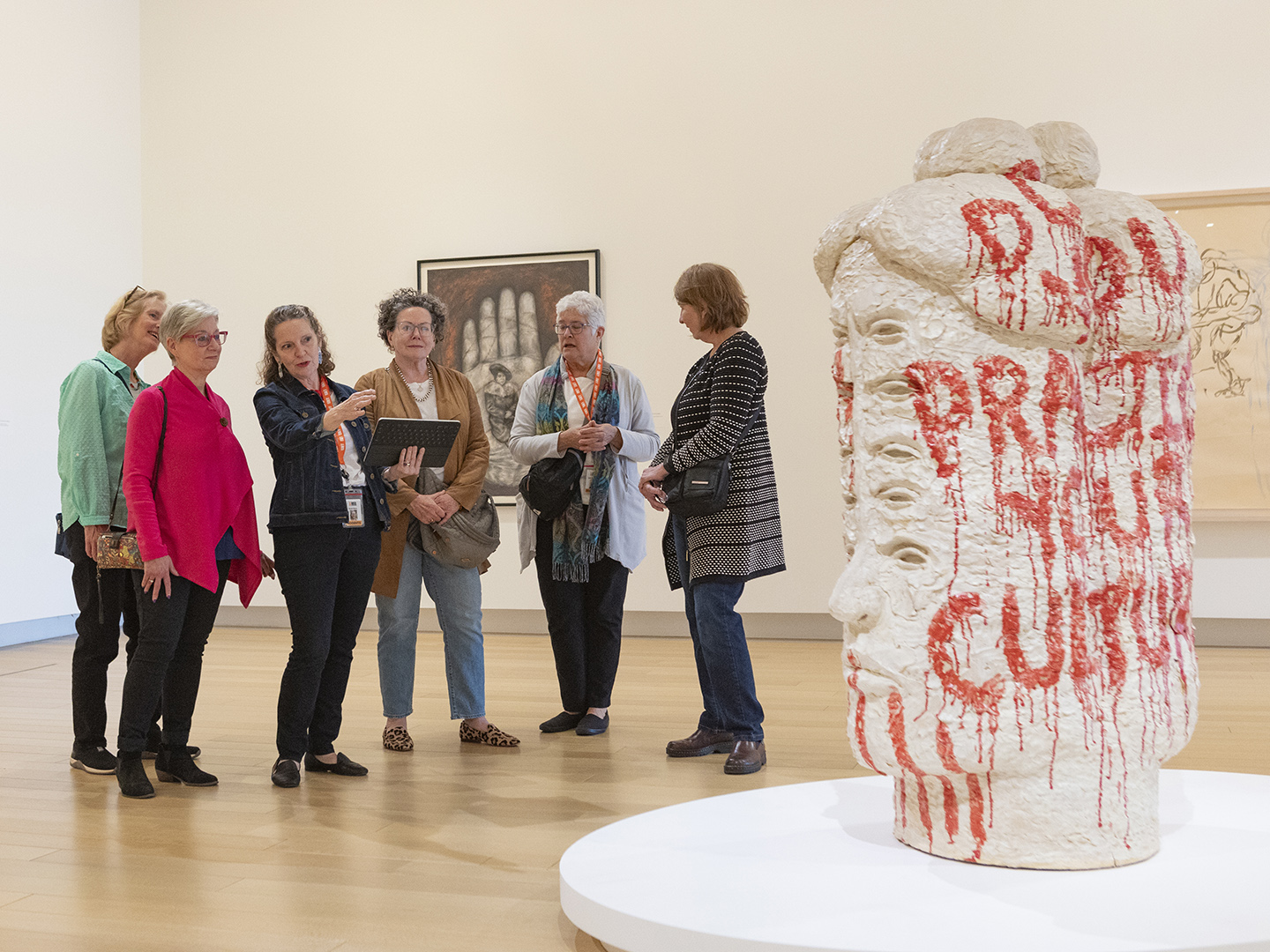 Photo of an AMFA docent with a group of women looking at a sculpture in an art gallery.