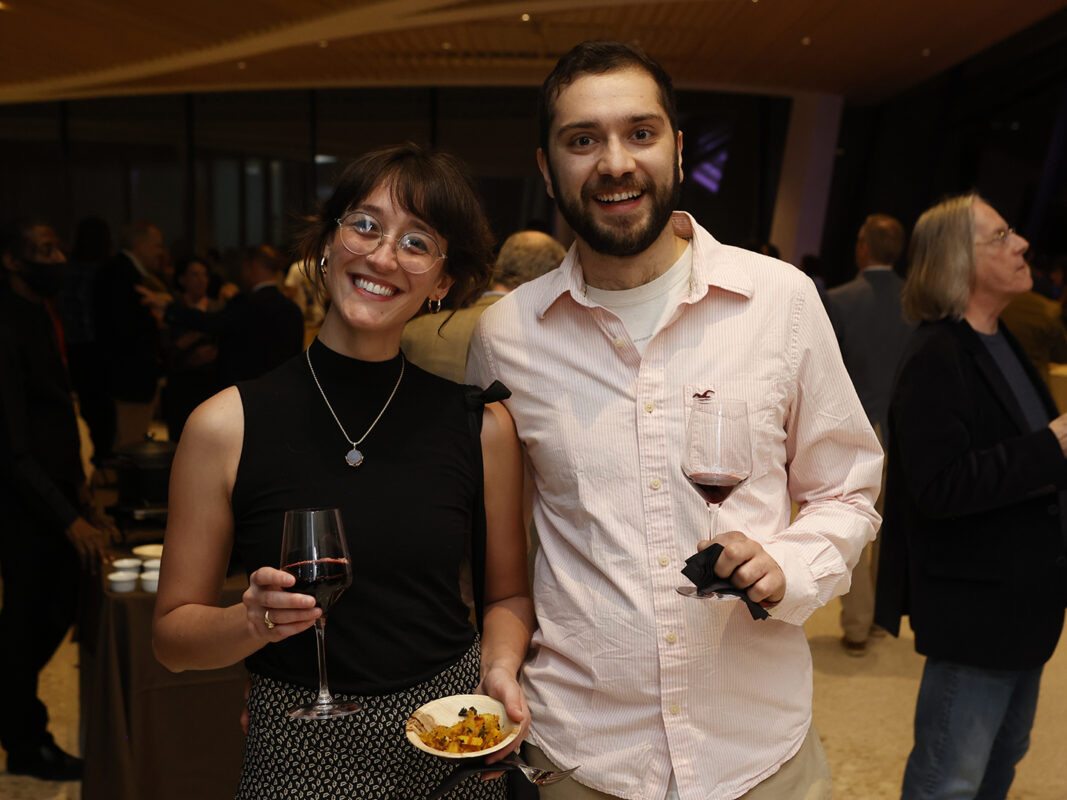Photo of a man and woman holding glasses of wine and a small bowl of food at an AMFA member party.