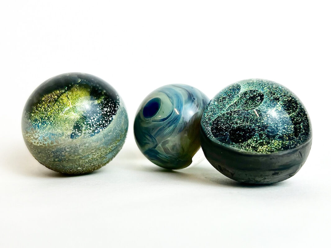 Photo of three glass marbles sitting on a white surface.