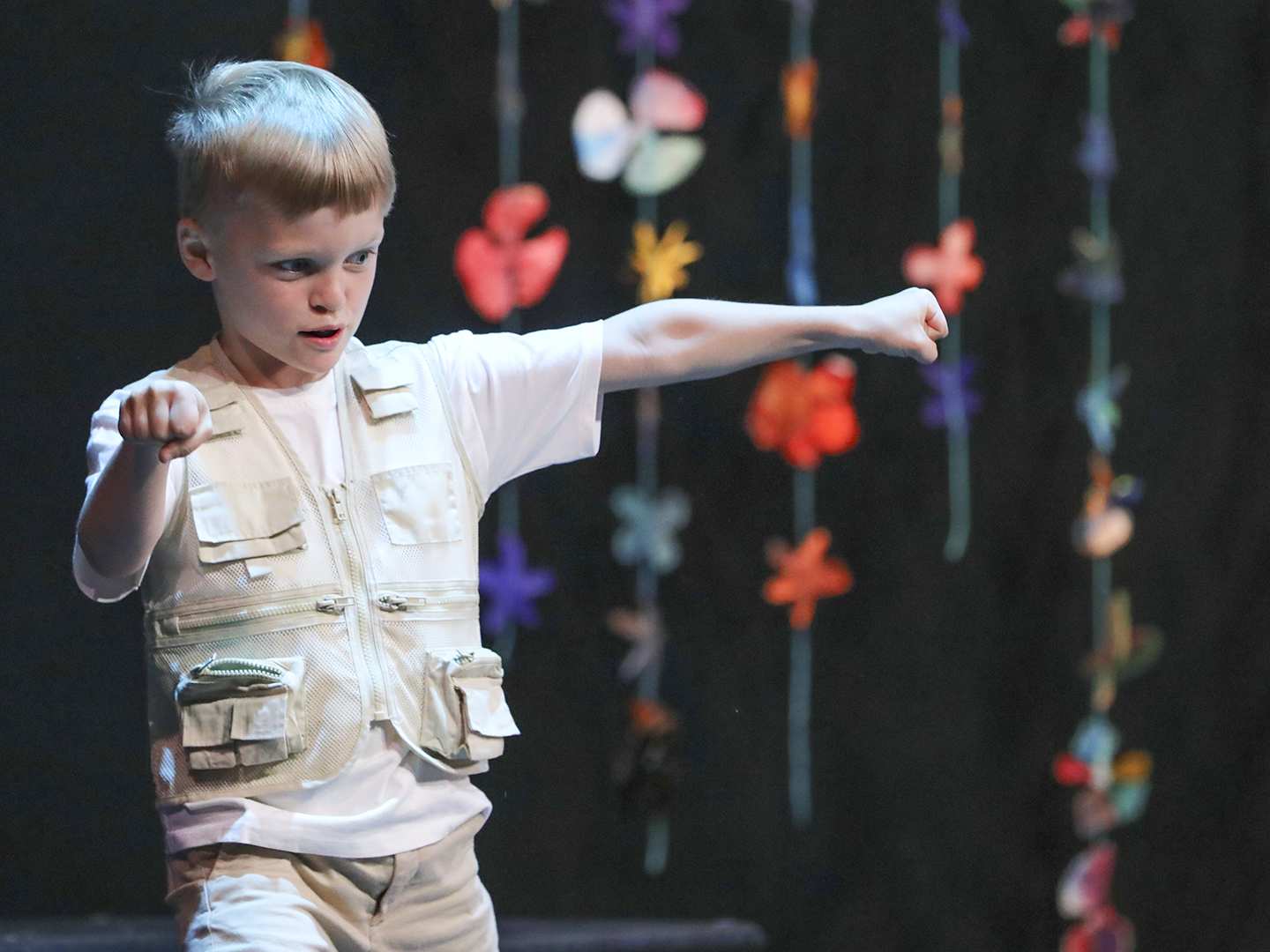 Photo of a young boy doing a dance move on a stage.
