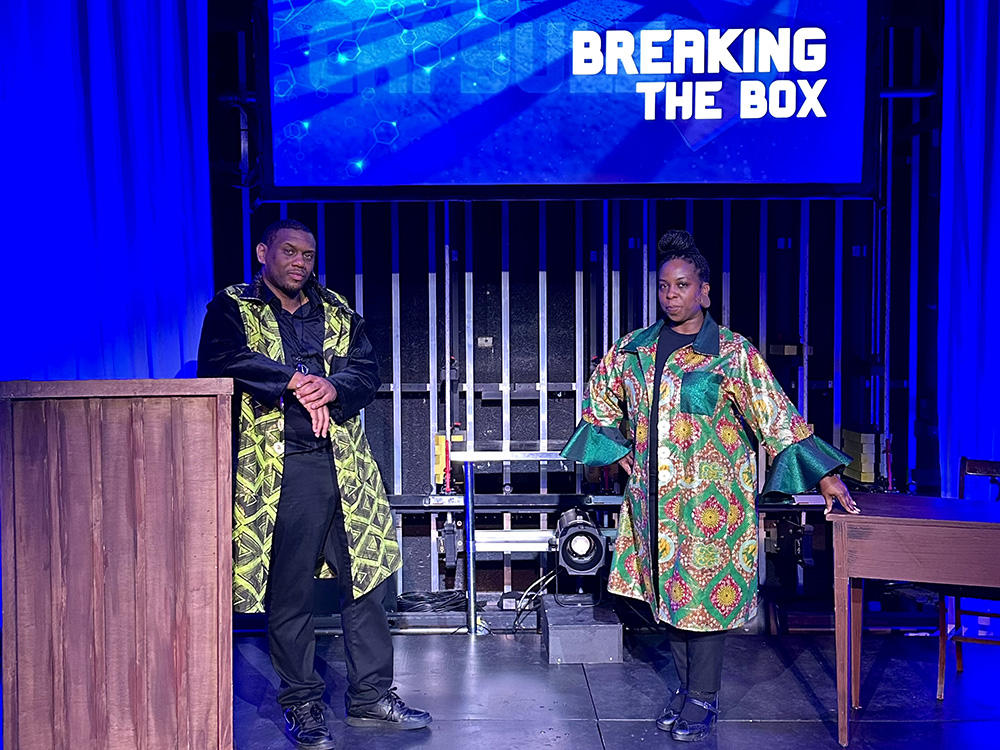 Photos of two actors in costume on a stage in front of a projection screen that reads Breaking the Box.