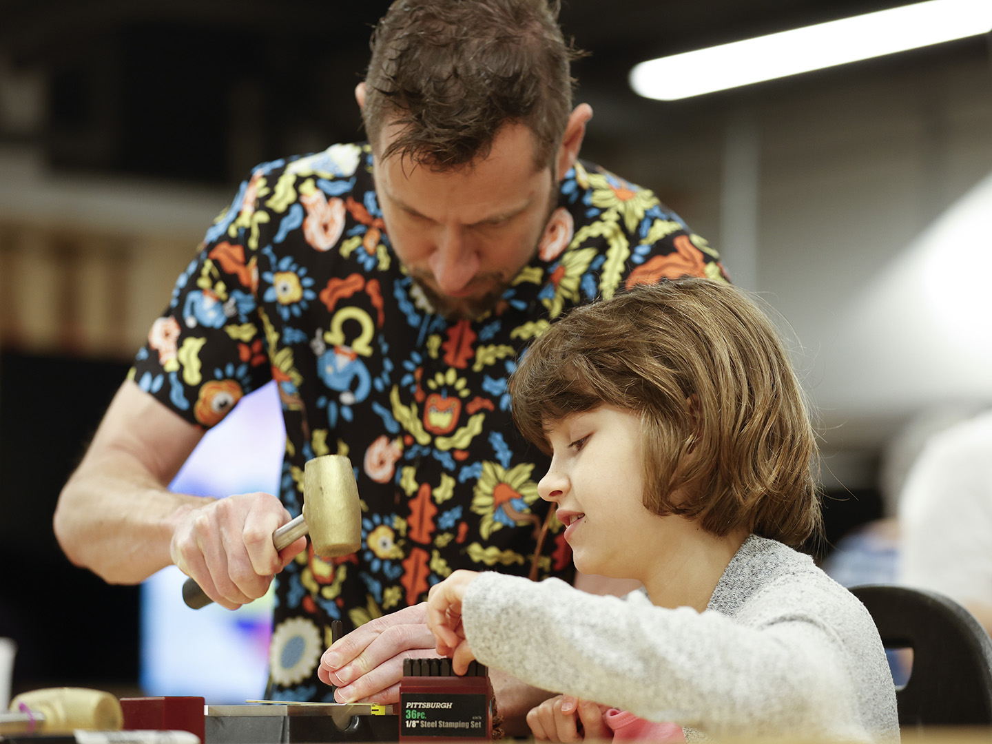 Photo of a father and young daughter working on a metal art project in a studio at the Windgate Art School.