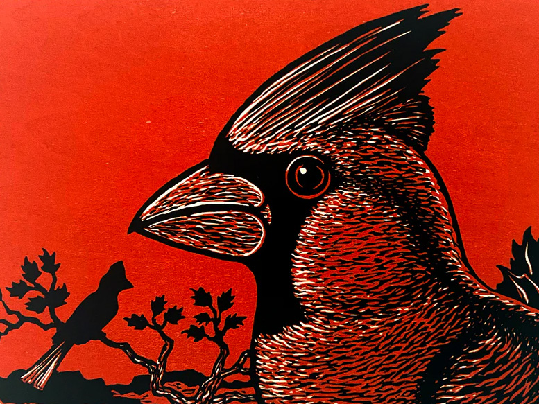 Detail photo of a woodcut print depicting a cardinal on a red background.