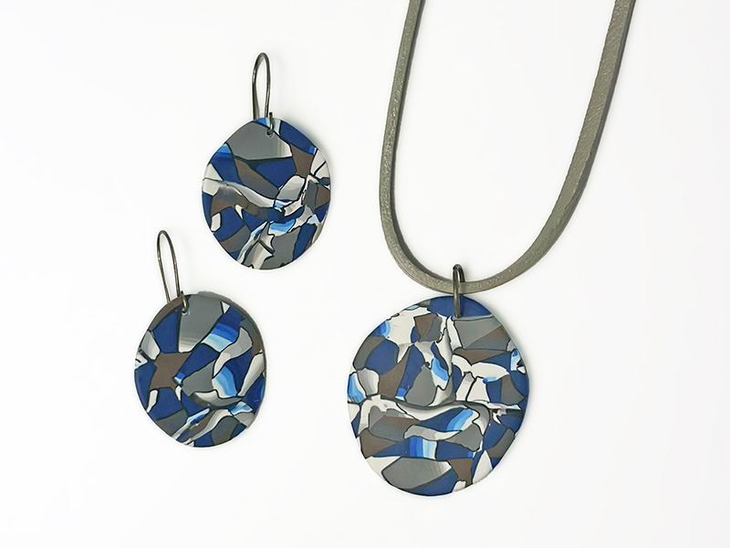 Photo of handmade Cubism-inspired earrings and a pendant on a silver necklace chain.