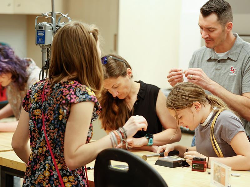 Photo of a man, woman, and two young girls doing an art-making activity in an art studio.