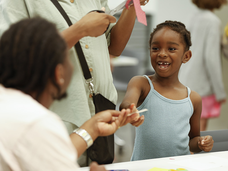 Photo of a young girl interacting with her father while working on an art activity.