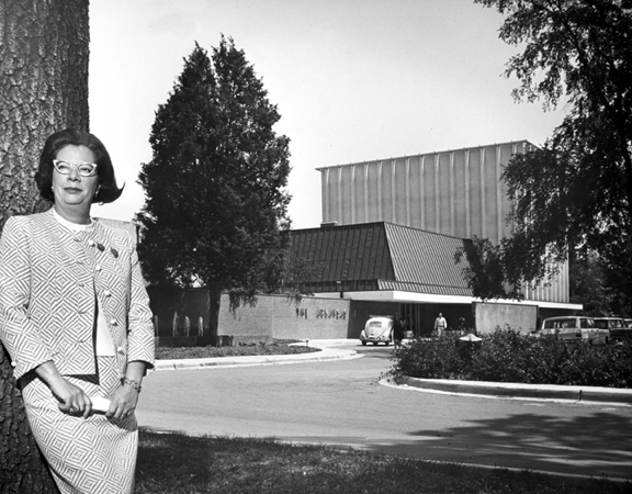 Black and white photo of Jeanette Rockefeller leaning against a tree in front of the Arkansas Arts Center in the 1960s.