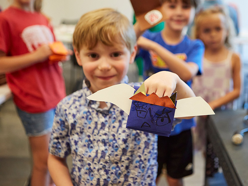 Photo of a young boy smiling and holding a handmade puppet.