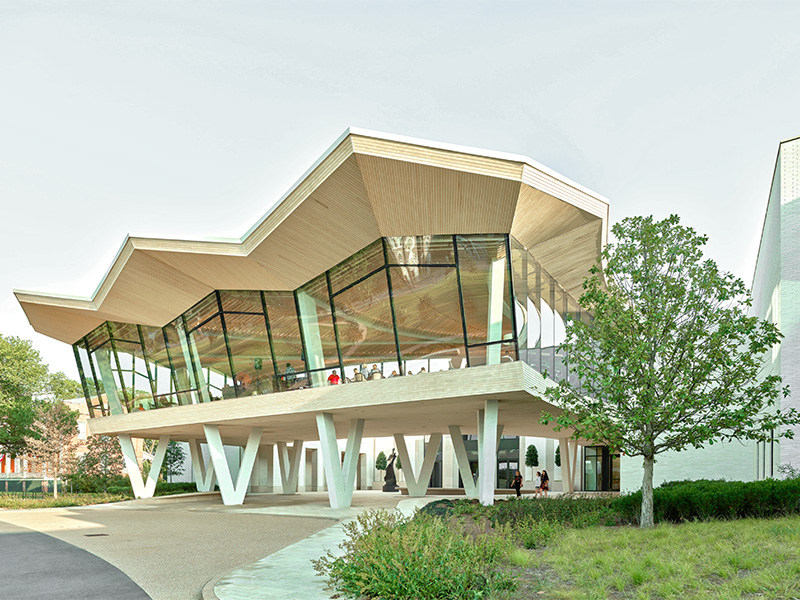 Photo of the Courtyard Entrance to AMFA. People are visible on the second floor through large glass windows.