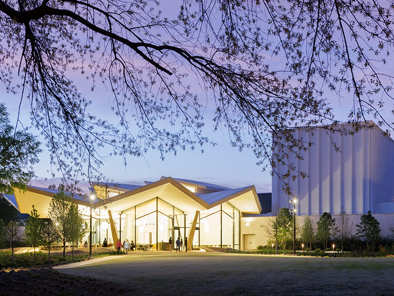 Photo of the Park Entrance to the Arkansas Museum of Fine Arts viewed from outside at night.