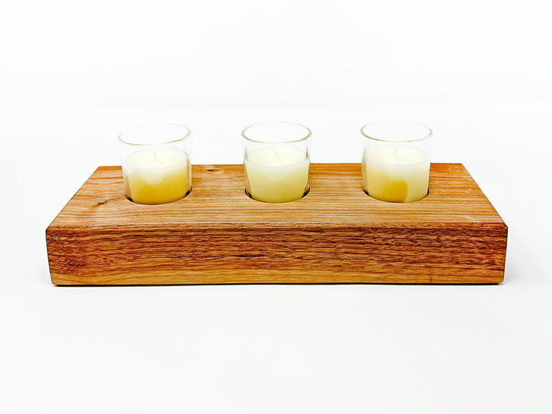 Photo of three votive candles sitting in a wooden holder.